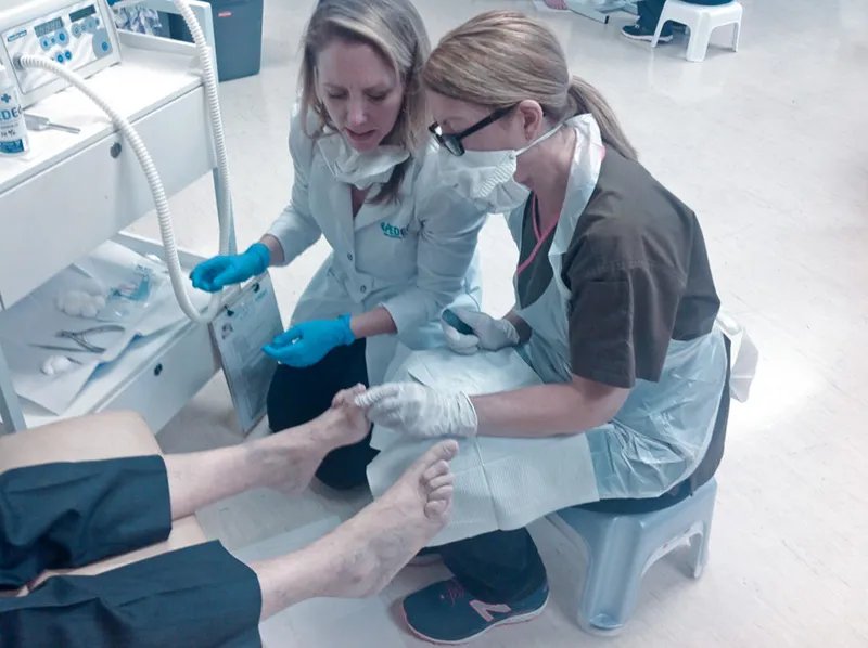 An educator guiding hands-on foot care during a clinical session
